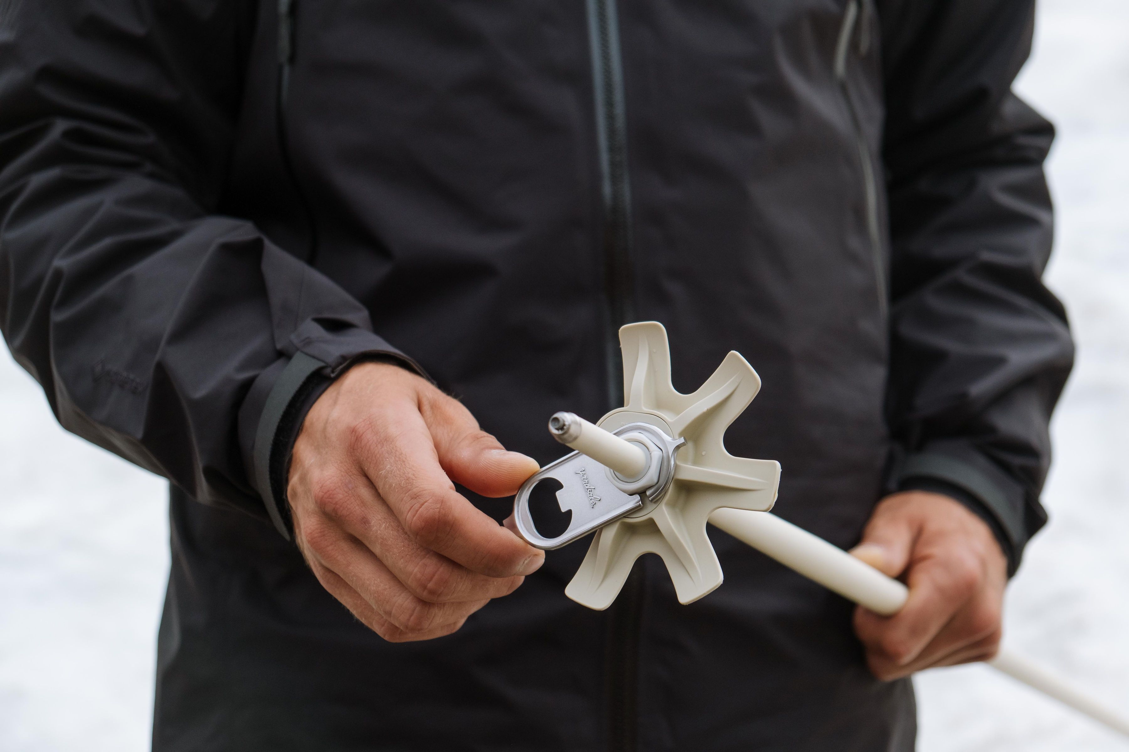 An image of someone screwing on a powder basket to a ski pole