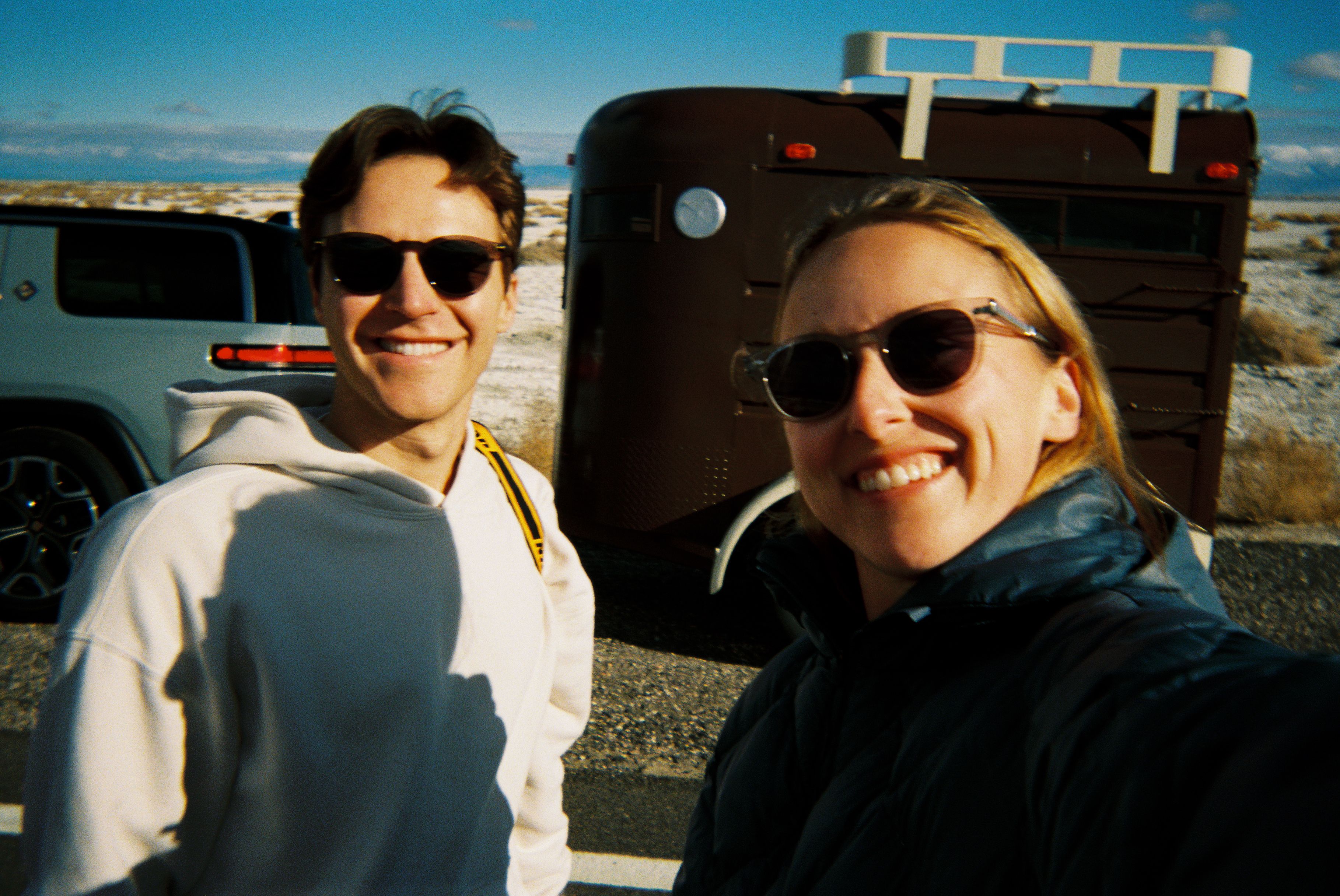 An image of two people smiling in front of a trailer