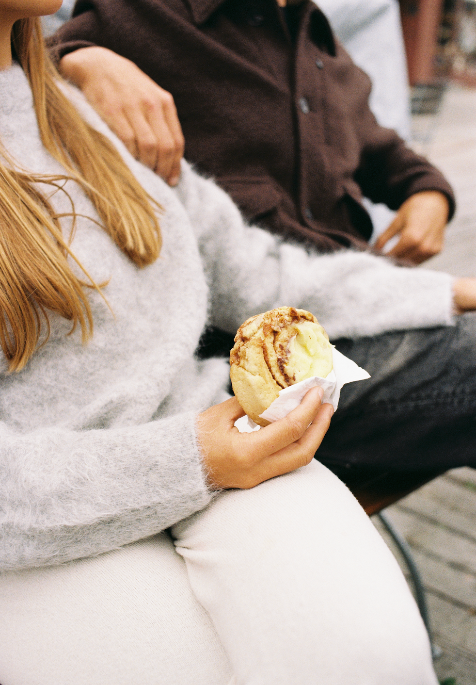 A woman in a cozy sweater eating a cinnamon roll