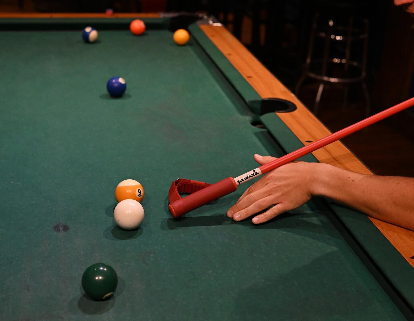 A red ski pole being used as a pool cue