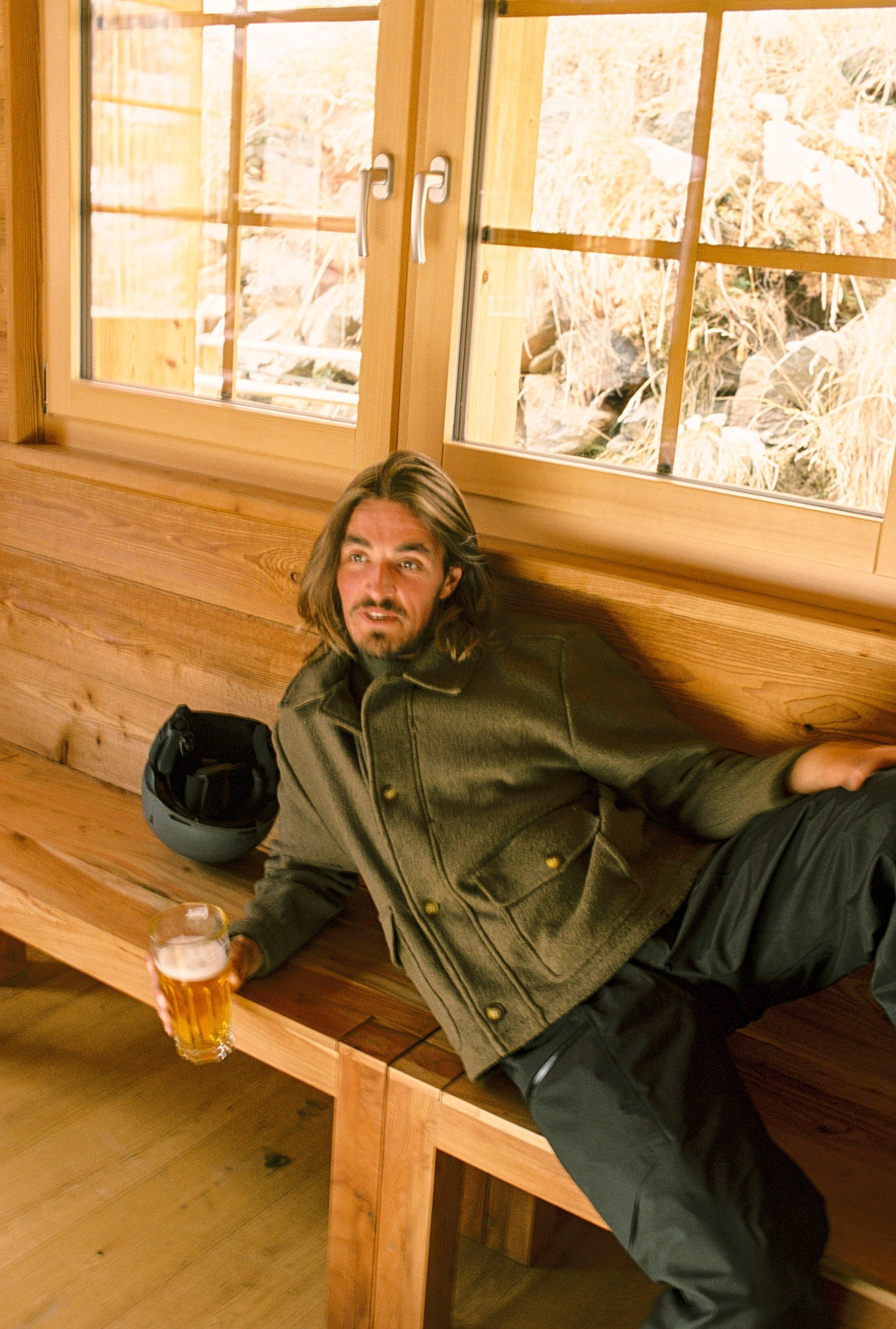 Image of a man lounging in ski gear with a beer