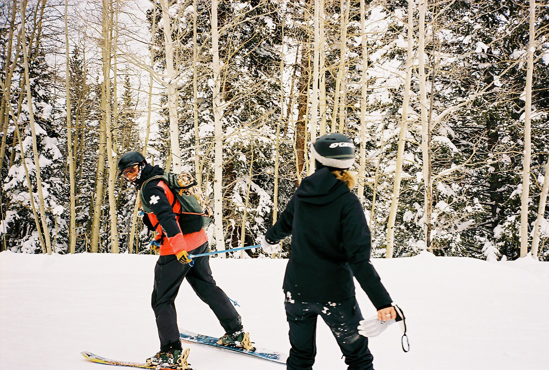 An image of a skier pulling someone with a ski pole 