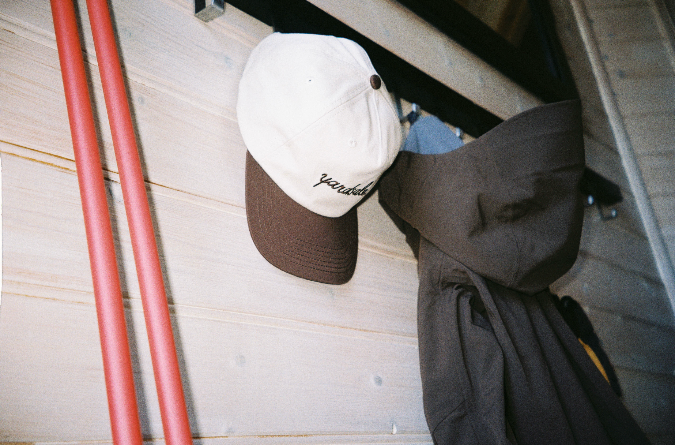 An image of a Yardsale hat and ski poles in a mud room