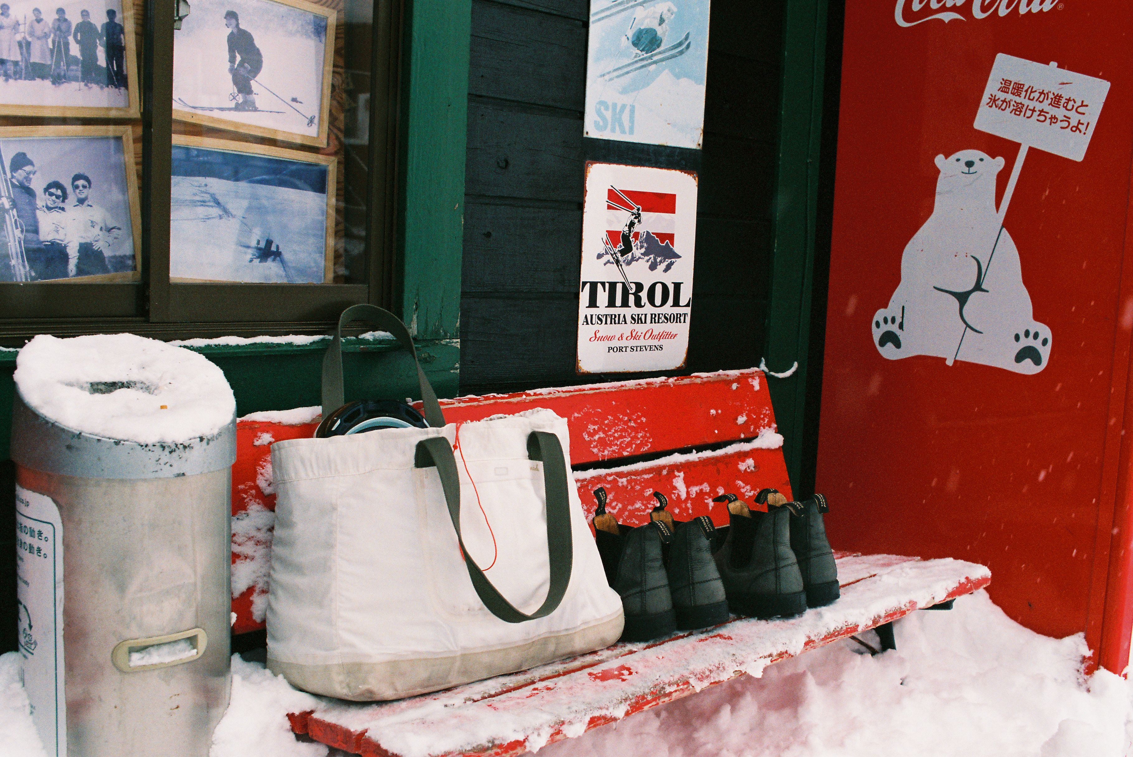 An image of a bag and boots on a snowy bench