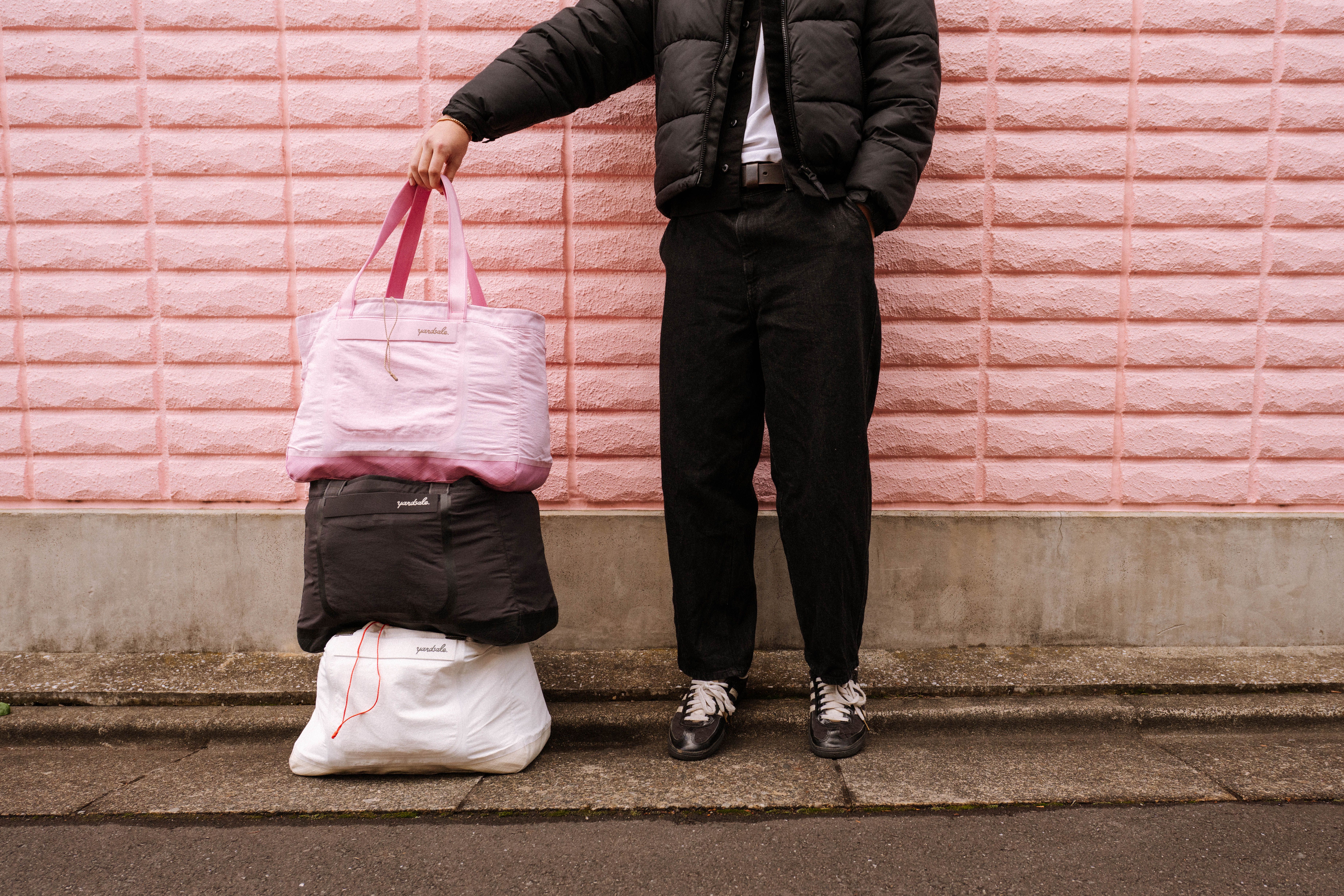 A stack of 20L Day Bags in front of a pink wall in Tokyo