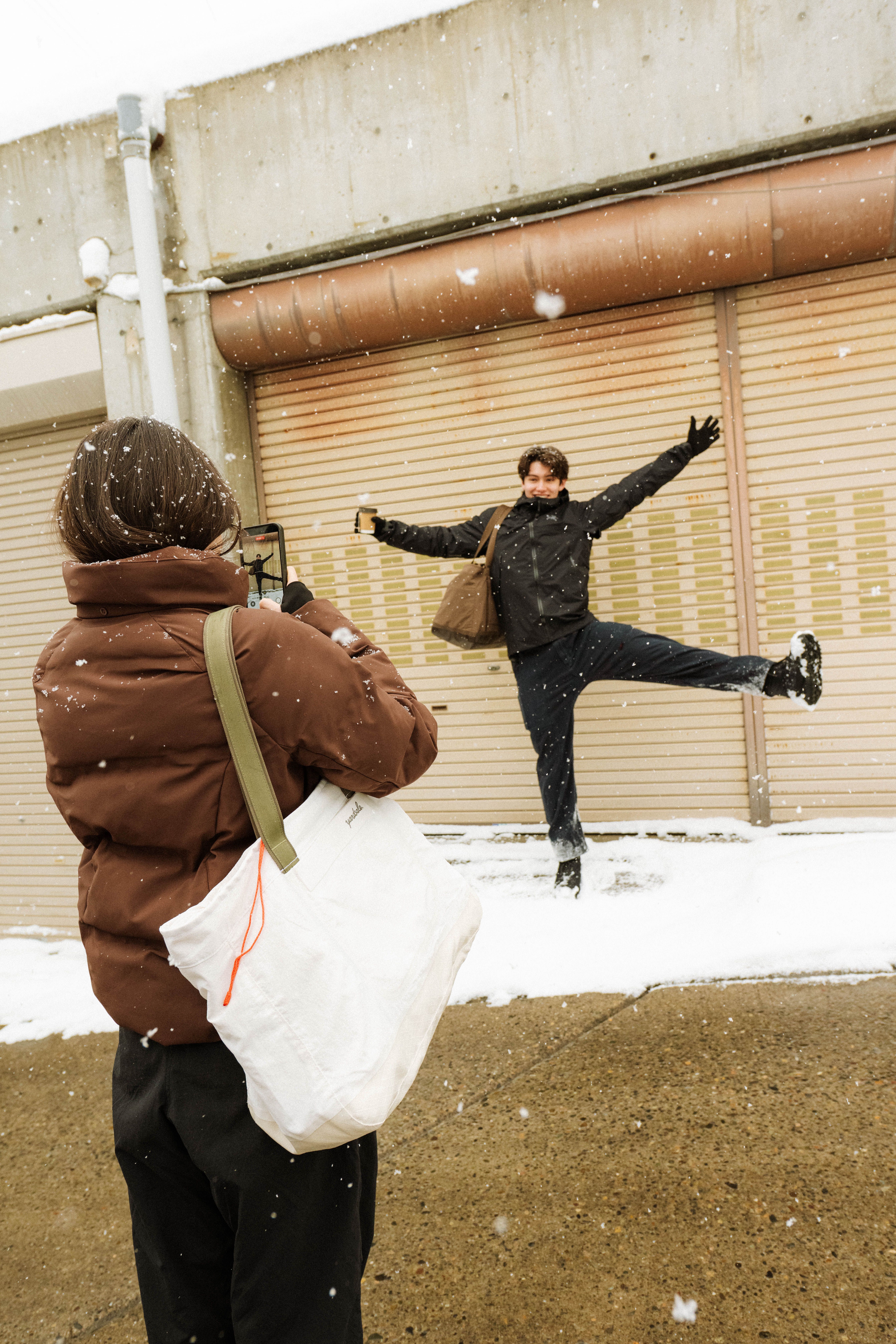 A photo of a woman taking a photo of a friend in the snow