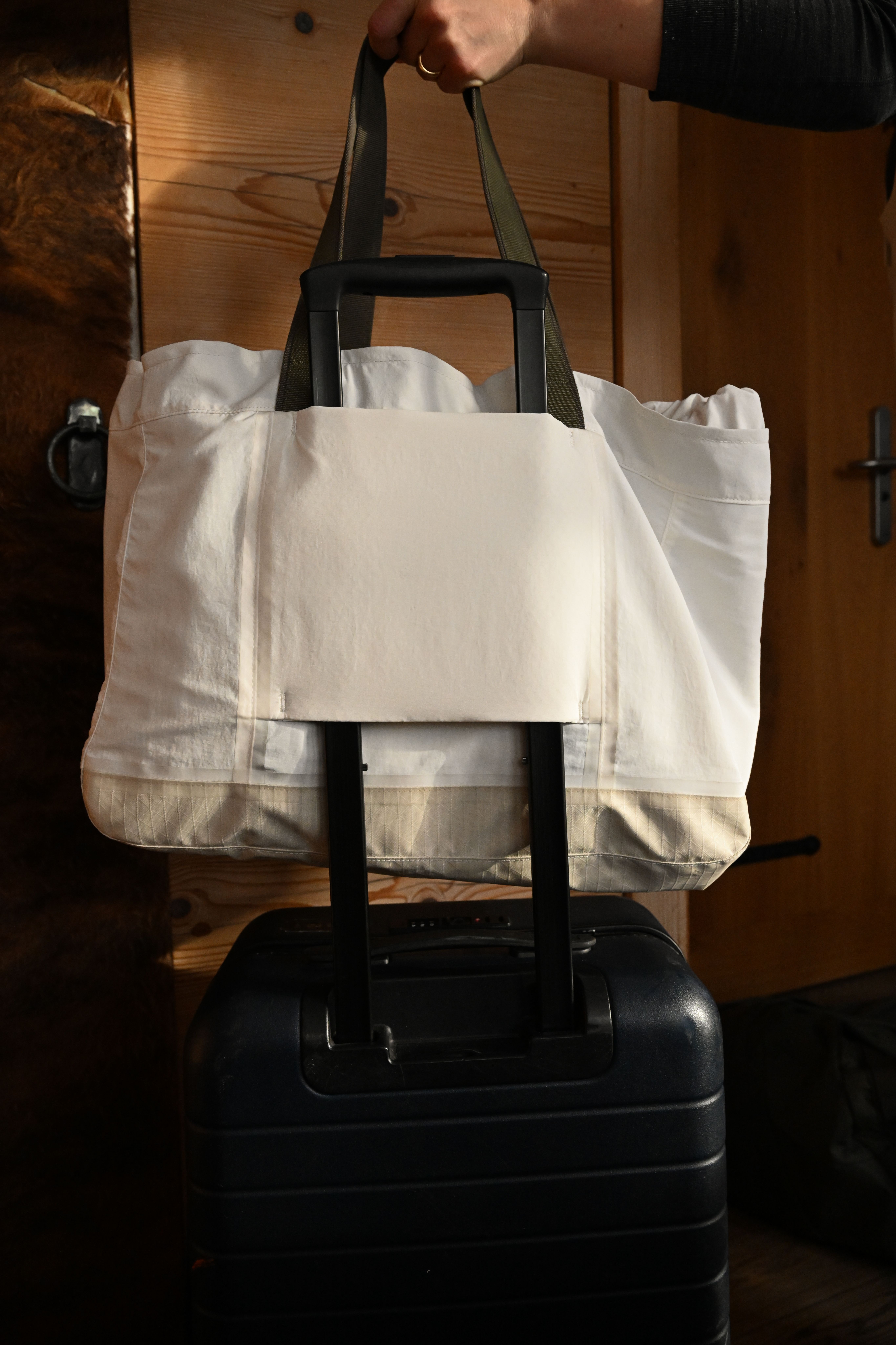 An image of a hand holding a bag on a suitcase