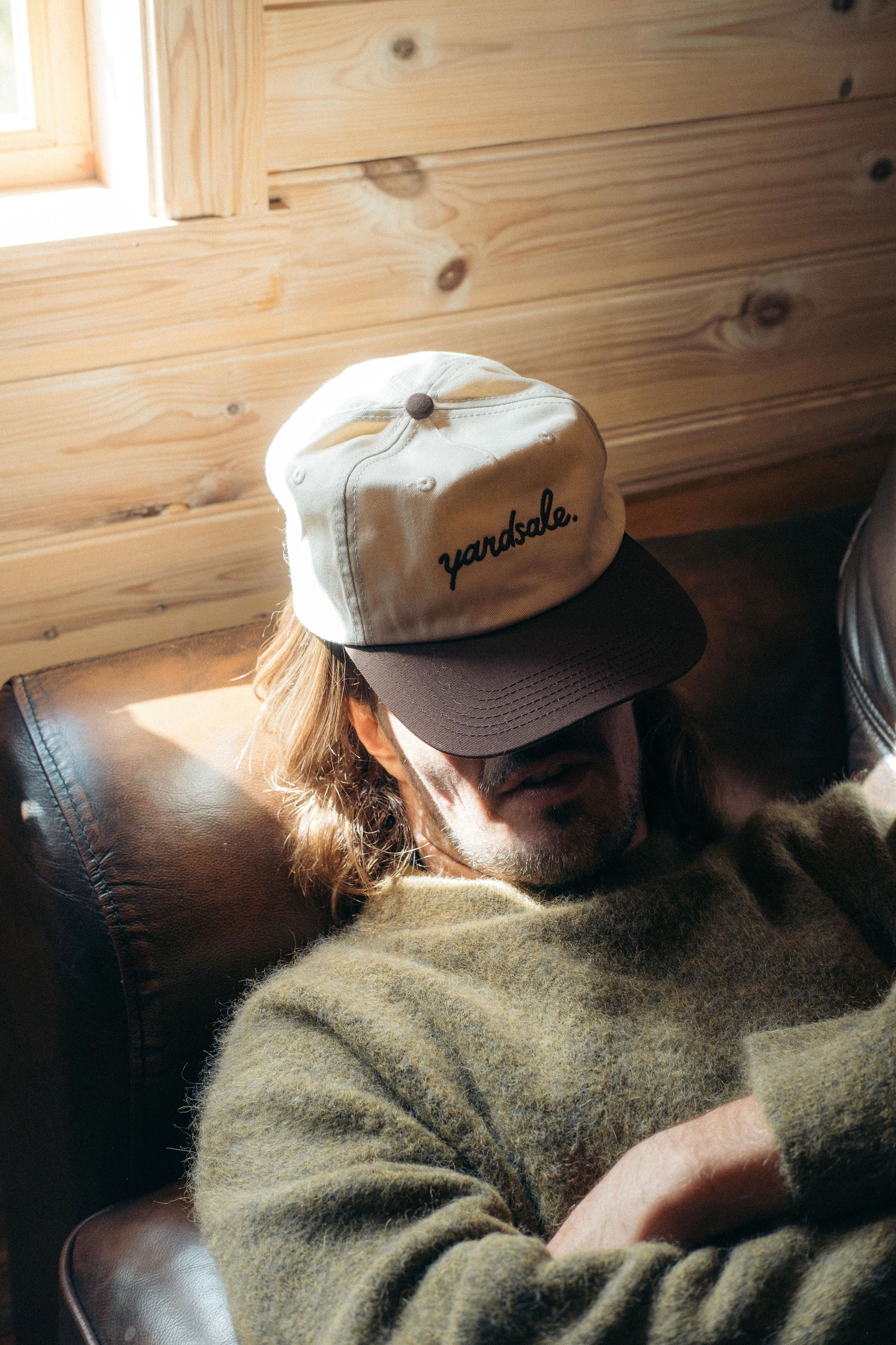 An image of a man with a hat covering his face
