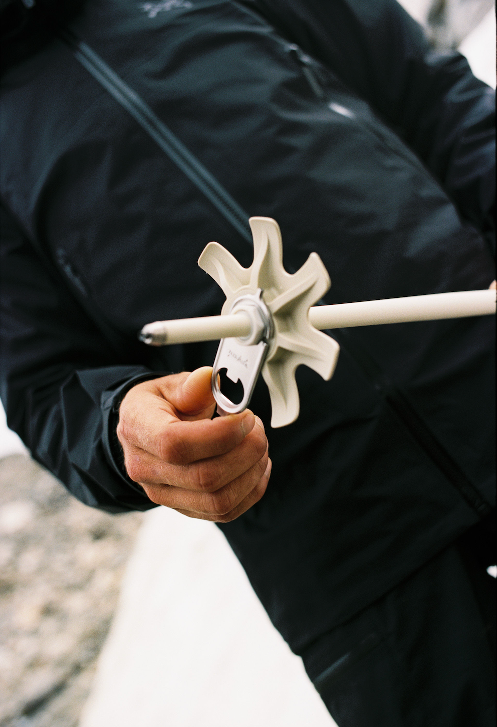 A skier attaching a powder basket to a ski pole